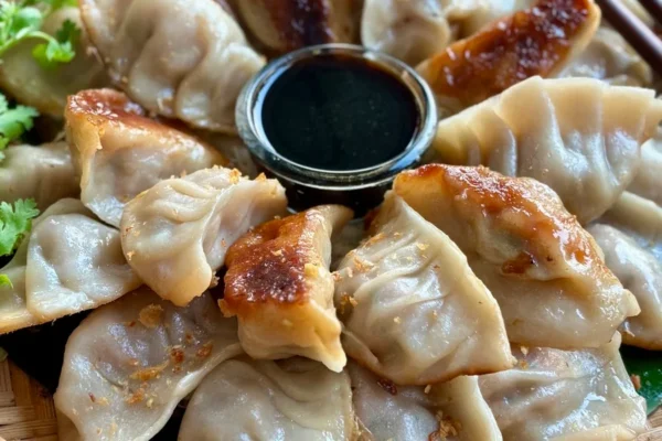 Pork gyoza with sauce on a traditional bamboo-woven dish.