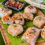 Golden-brown pan-fried rice paper dumplings filled with a meat and vegetable mixture, garnished with sesame seeds and spring onions.