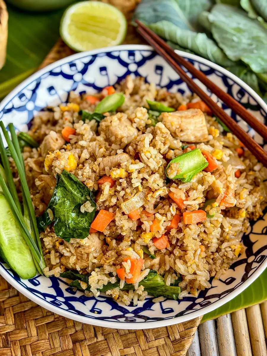Khao pad gai, chicken Thai fried rice, with crispy vegetables, eggs, and a side of lime and fresh cucumbers.