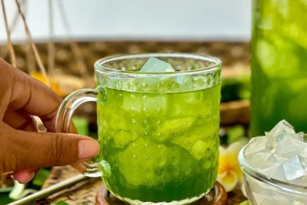 Thai Pandan Drink Recipe (Nam Bai Toey) Thai pandan drink with chewy jelly cubes, served on a woven mat with pandan leaves.
