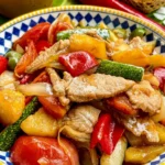 Close-up of Thai sweet and sour pork stir-fry with fresh vegetables.
