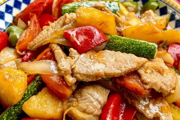 Close-up of Thai sweet and sour pork stir-fry with fresh vegetables.