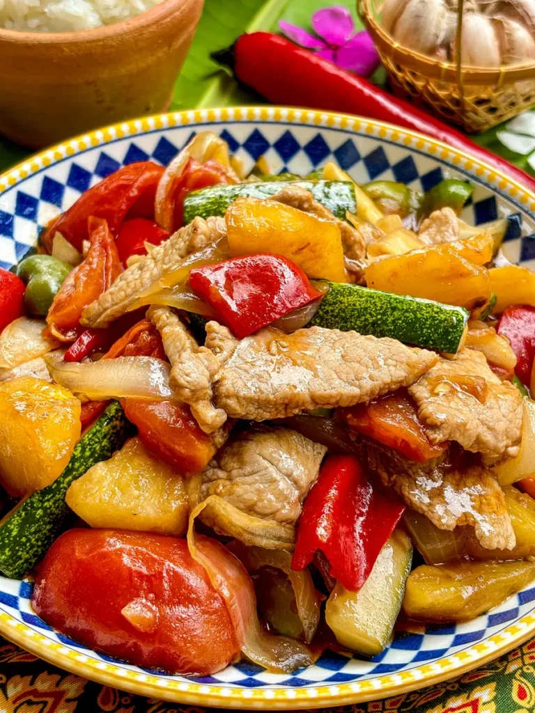 Close-up of Thai sweet and sour pork stir-fry with fresh vegetables.