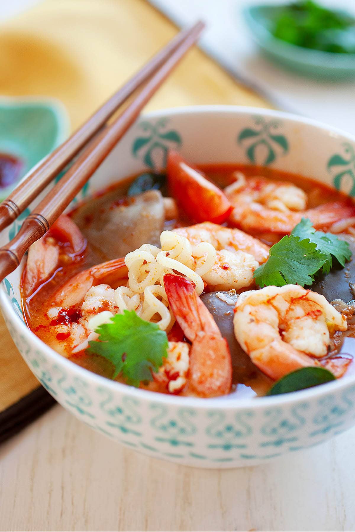 Tomyum noodle soup served in a bowl with a pair of chopsticks.