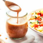 Creamy balsamic dressing drizzled in jar with a spoon.