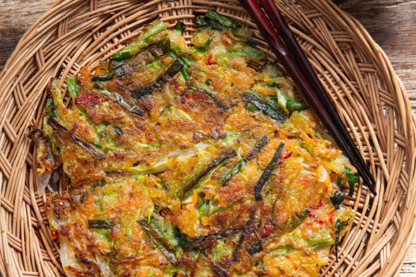 Crispy yachaejeon served on a woven basket plate
