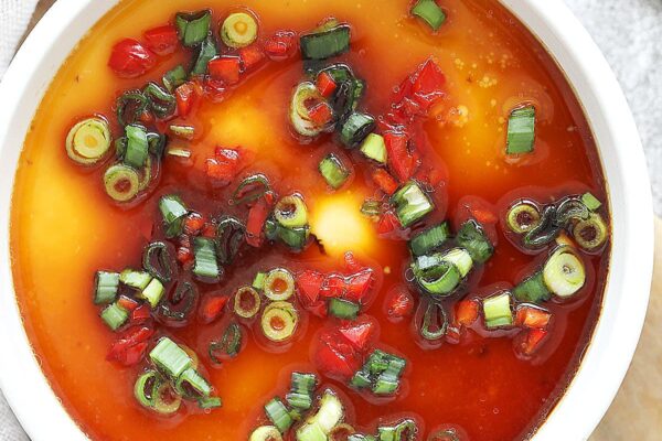 Chinese steamed eggs garnished with chopped scallions and red chili.