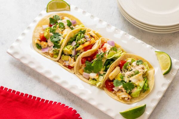platter of fish tacos with toppings and lime wedges