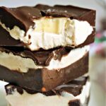 A stack of 3 ice cream bars with the top one hal bitten to reveal a slice of banana inside.