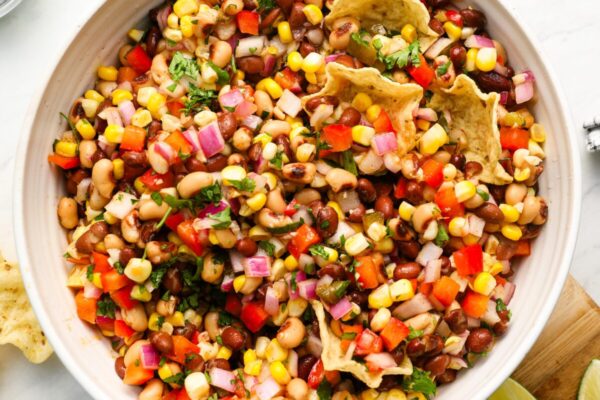 Cowboy Caviar Recipe – A Hit at Every Party cowboy caviar in serving bowl with chips, cilantro and lime