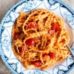 Pasta ribbons in a creamy  tomato sauce in a blue and white vintage style bowl with sauteed cherry tomatoes on top.