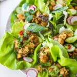 Thai tofu larb in butter lettuce wraps garnished with sliced cucumber and radish and chliies.