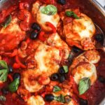 a stainless steel skillet of chicken pizzaiola with olives, mushrooms, and cheese.