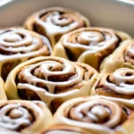 Delicious protein cinnamon rolls, freshly baked and glazed, in a baking dish.