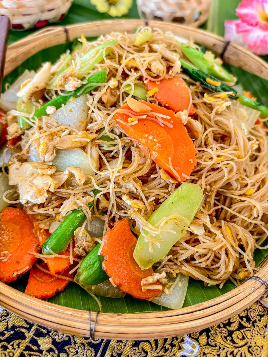 Thai pad see ew with sen mee rice noodles, carrots, Chinese broccoli, and chicken served in a bamboo plate.