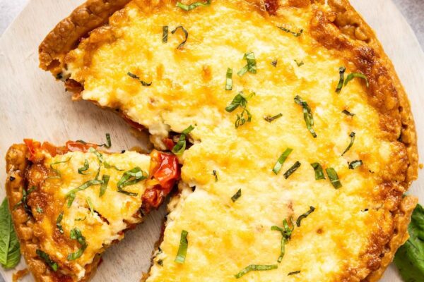 southern tomato pie on platter with tomatoes on the table