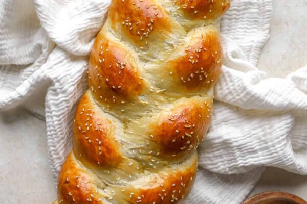 A baked loaf of Challah bread topped with sesame seeds.