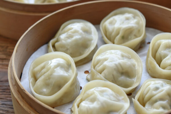 Steamed mandu served in a bamboo steamer basket
