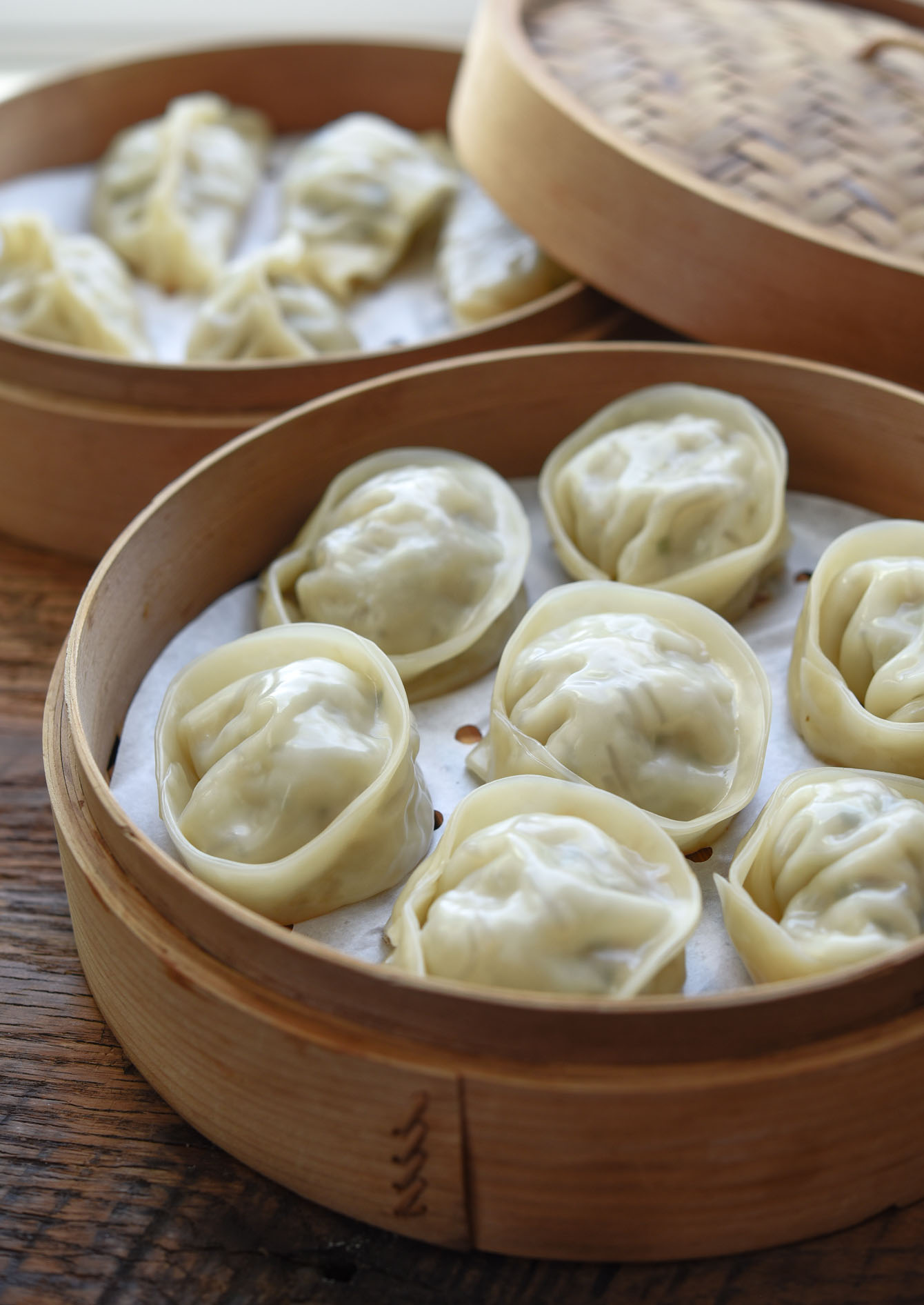 Steamed mandu served in a bamboo steamer basket
