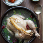 Whole samgyetang (Korean ginseng chicken soup) served in a bowl with ginseng garnish