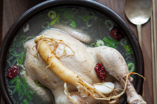 Whole samgyetang (Korean ginseng chicken soup) served in a bowl with ginseng garnish