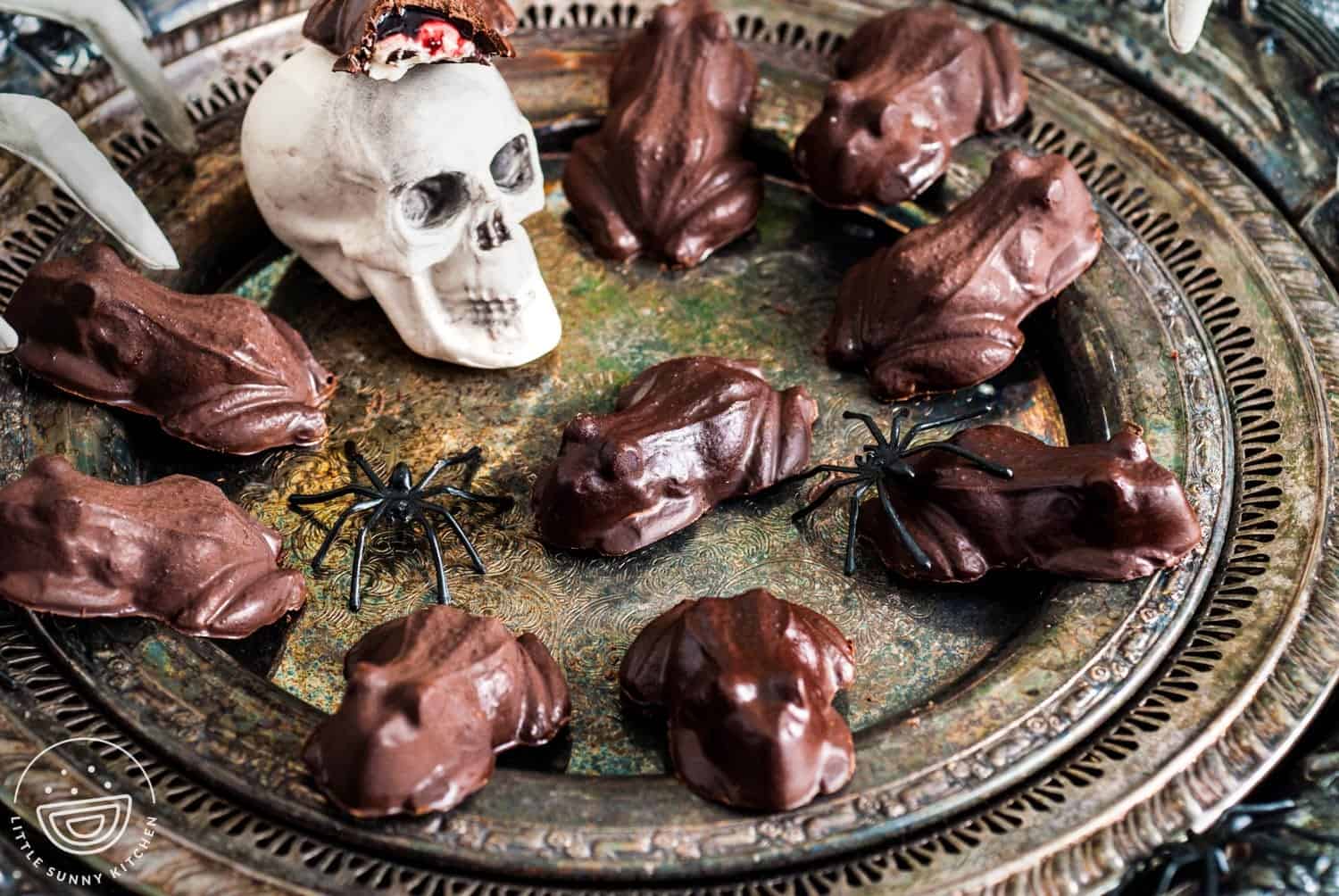 Homemade chocolate frog candies on an antique silver tray, with a small plastic spider decoration for a spooky Halloween touch.